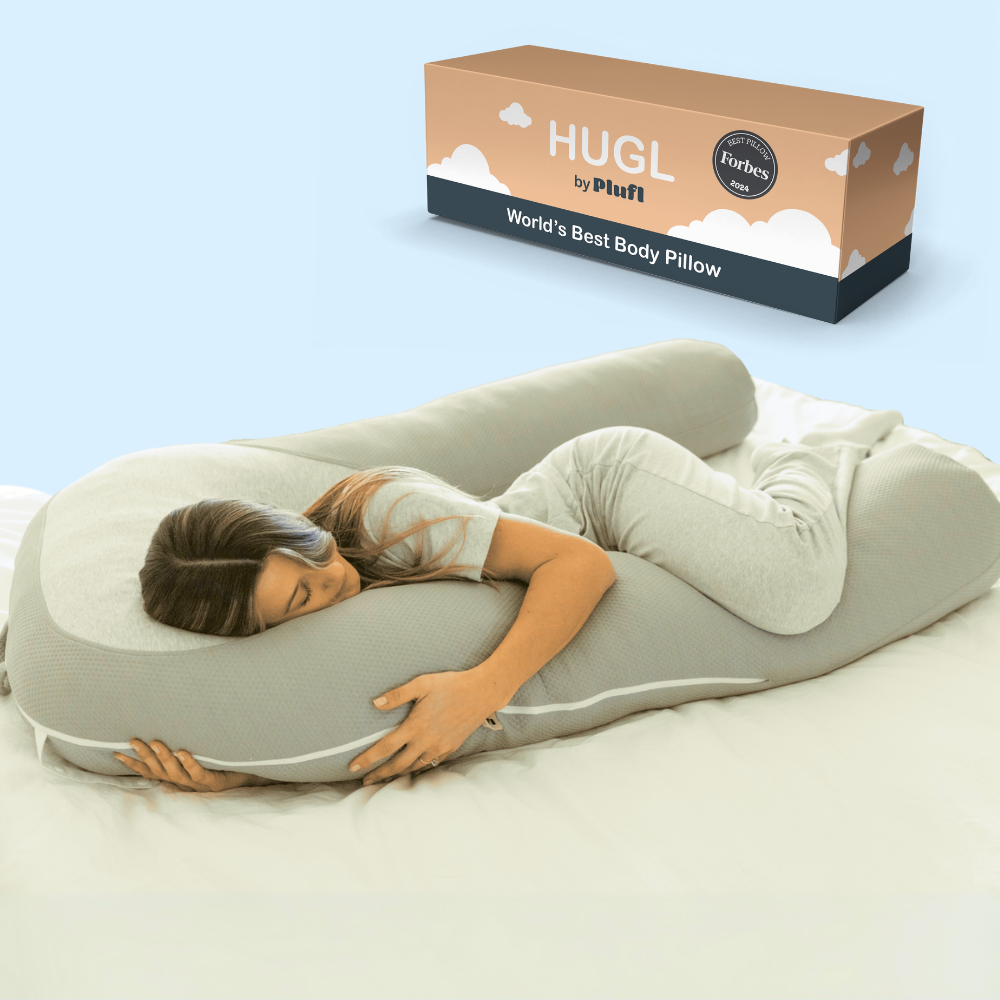 Woman asleep hugging the Hugl body pillow, with the Hugl packaging box shown behind